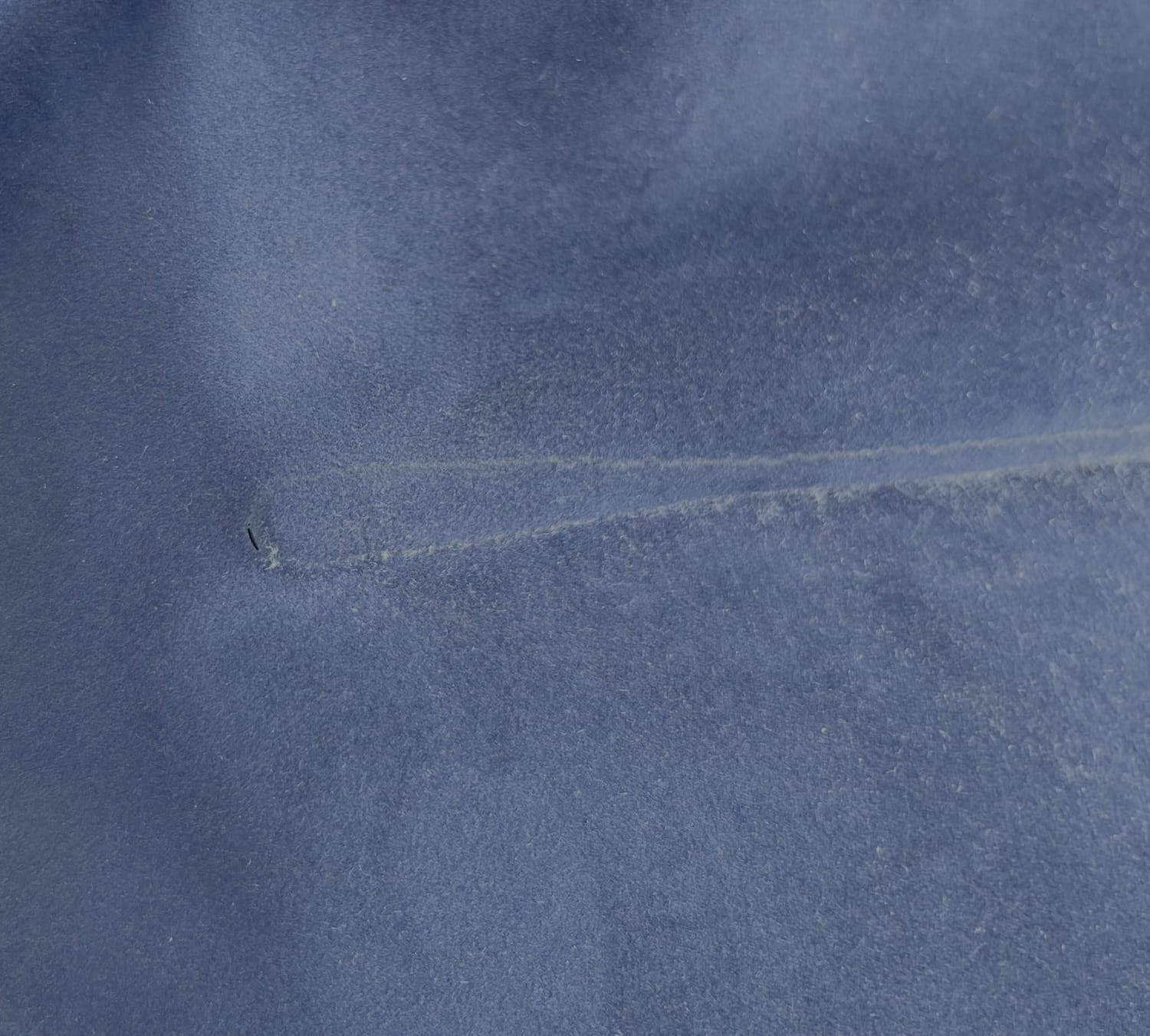 Klein gaatje zichtbaar in de blauwe fluwelen bovenkant van een luchtbed