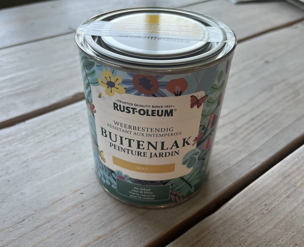 Pot Rust-Oleum buitenlak in het geel, klaar voor gebruik op een houten schutting