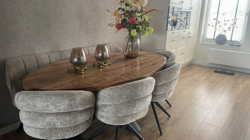 Stoffen eetkamerstoelen met zwart draaionderstel rond een ovale houten eettafel